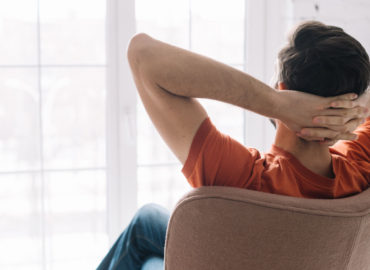 foto de homem sentado em uma cadeira com as mãos na nuca em posição de relaxamento de