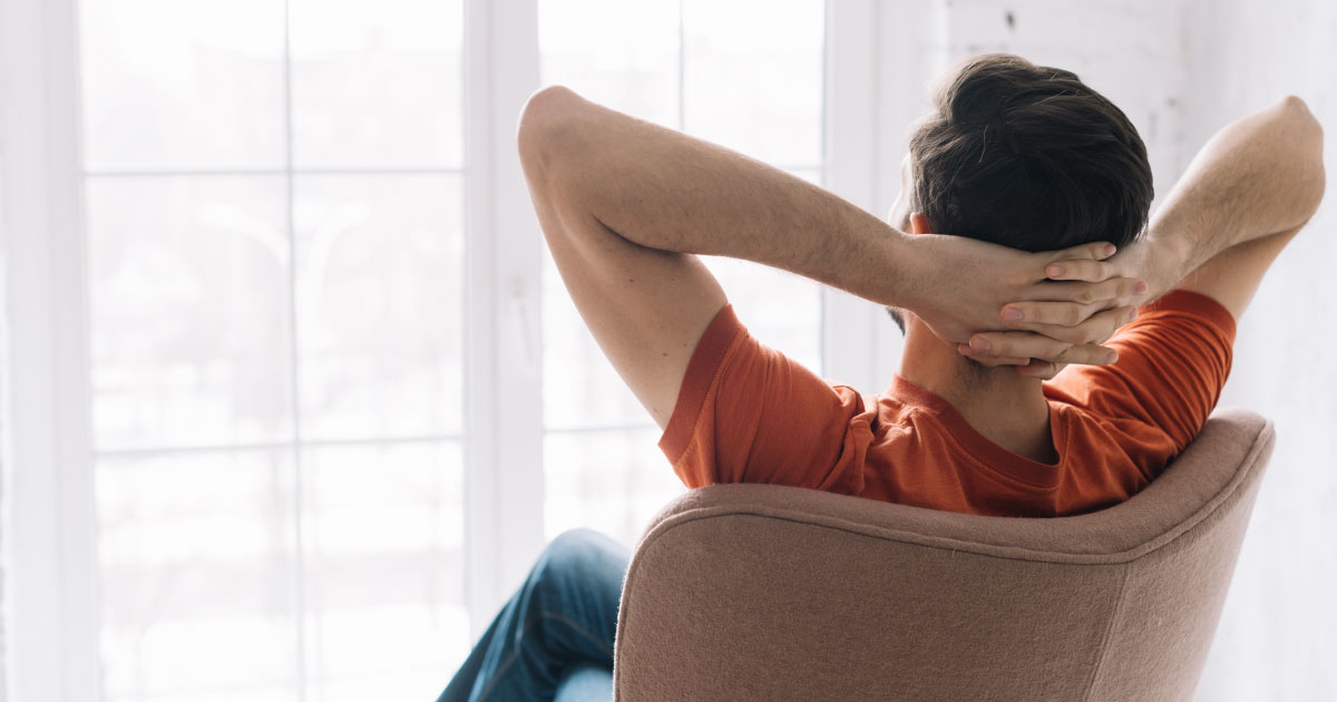 foto de homem sentado em uma cadeira com as mãos na nuca em posição de relaxamento de