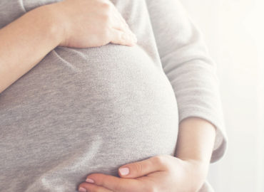 foto de uma grávida com as mãos na barriga