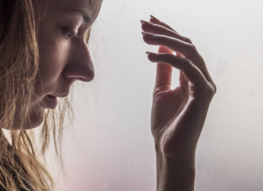 foto de rosto de mulher de lado, de olhos fechados e uma das mãos à frente