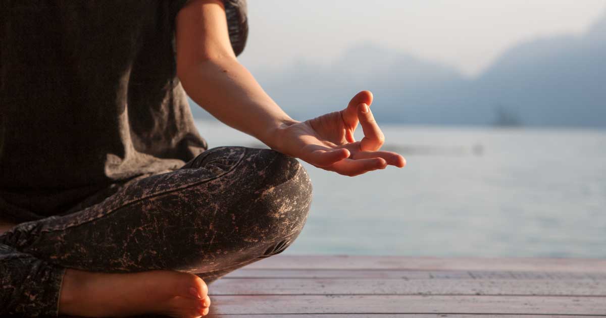 foto de uma mulher meditando com um mar ao fundo