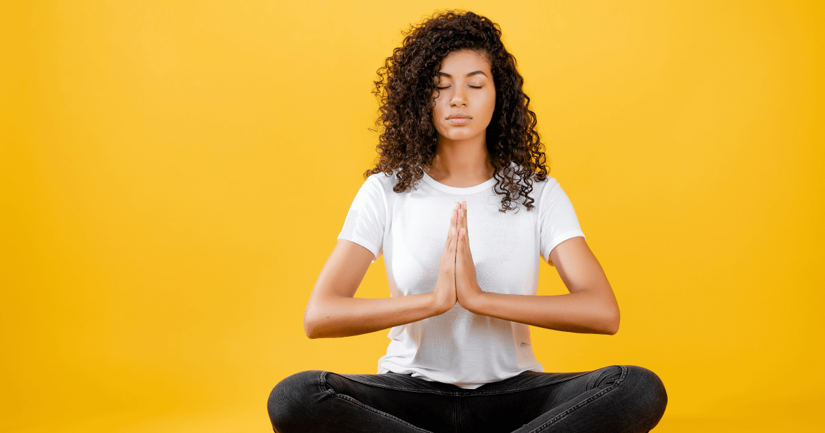 Foto de uma mulher negra meditando em fundo amarelo